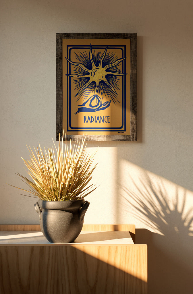 Radiance linocut print by Belgian artist Leda Vaes featuring a golden abstract sun with blue rays and a hand illustration on handmade paper in A4 format.