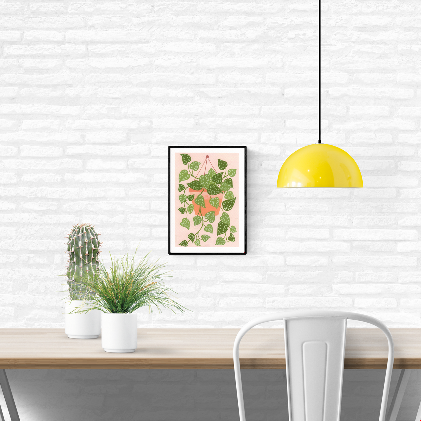 Digital art print titled “Scindapsus” by Belgian illustrator Leens, featuring a lush cascading houseplant with heart-shaped green leaves in a terracotta hanging pot, against a soft pink background. Printed on A4 fine art paper.