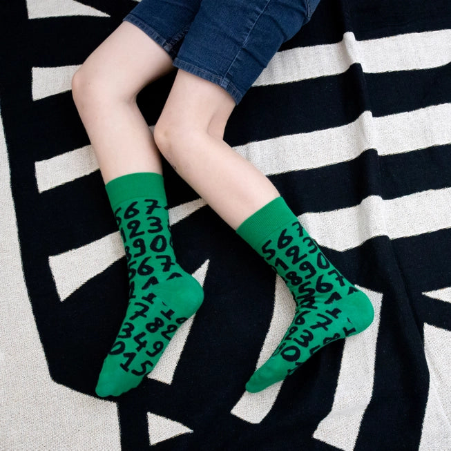 Green crew socks with playful black numbers by Sarah Corynen – unisex cotton blend, size 38-42, bold and quirky design for math fans and creative wardrobes.