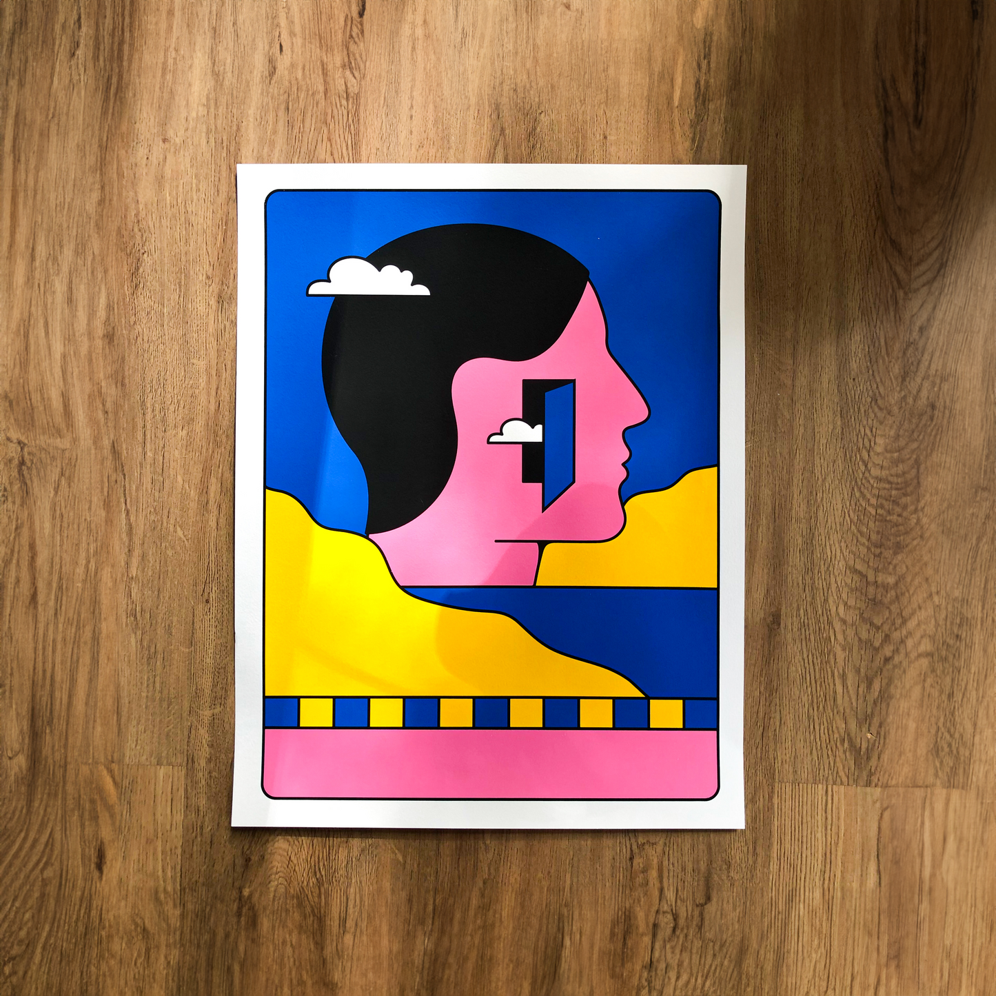 Colorful silkscreen print of a modern pink, blue, yellow graphic human face by PTRVRKD, titled Wanderer, on 50 x 65 cm 300 gsm Carson paper. Limited edition handprinted art with bold pop art style.