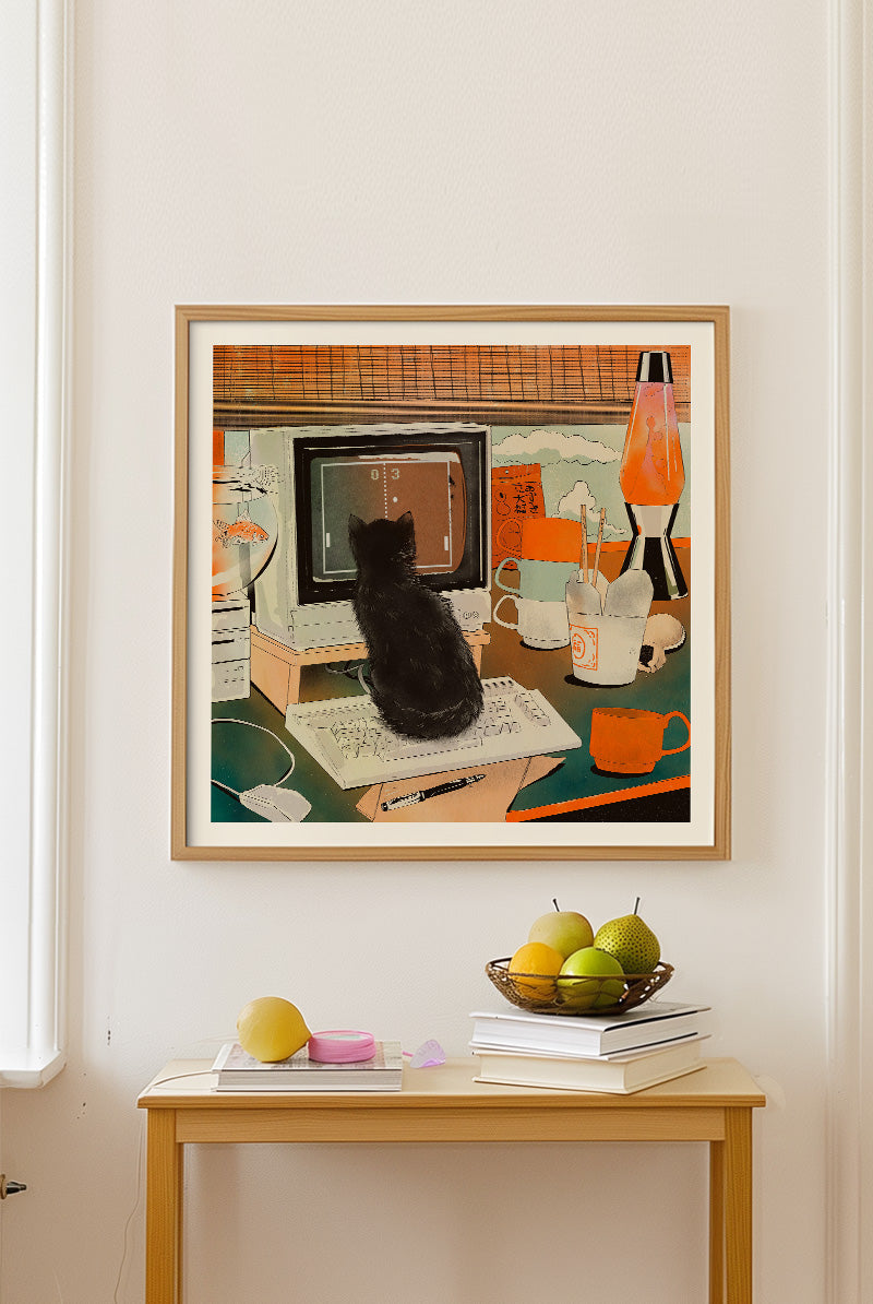Retro Gaming Cat art print by Enikő Eged, featuring a black cat sitting on a desk in front of a vintage computer game, surrounded by retro home decor, warm orange tones, a lava lamp, coffee cup, and playful nostalgic details.