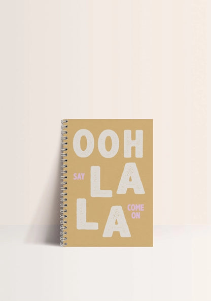 A5 spiral notebook titled “Ooh La La” by Papier & Co., featuring bold white typography on a warm brown cover with pastel pink accents, 60 blank recycled pages – French-designed eco-friendly notebook for creatives and design lovers.