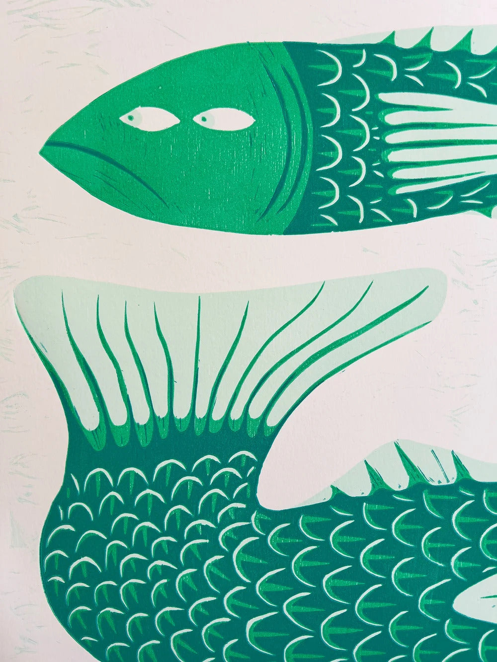 Limited edition risograph art print titled Gill Behaviour by Northern Irish artist Strangford. The artwork features two green fish with expressive eyes, intertwined in a surreal underwater embrace. Printed on recycled A3 paper using linocut and oil-based inks. Edition 56 of 93. Bold, quirky, and handmade—perfect for collectors and lovers of whimsical animal art.