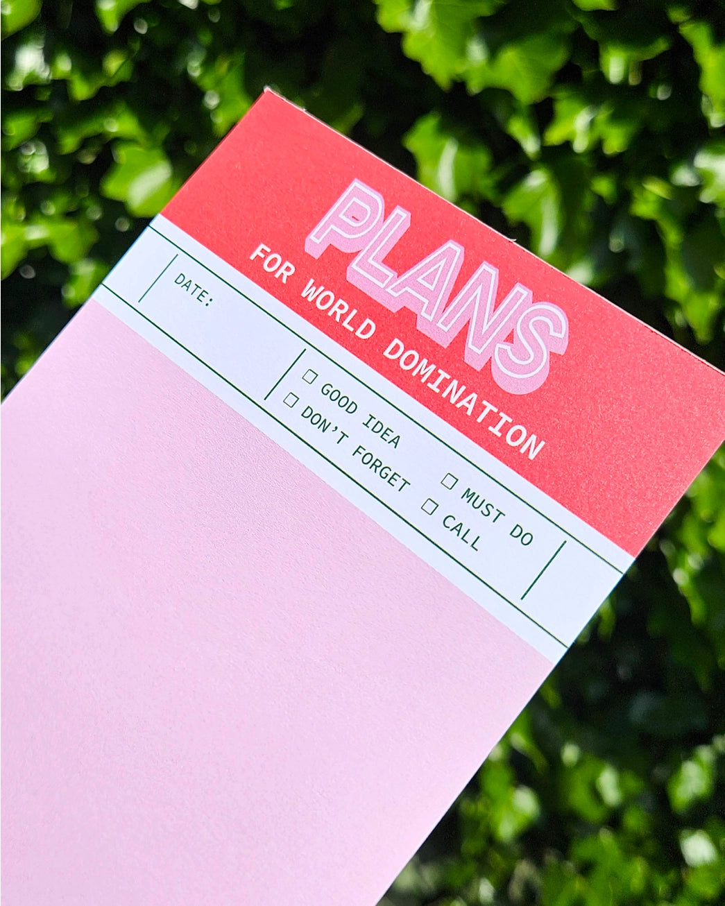 Funny red and pink notepad titled “Plans for World Domination” by Studio Inktvis, A6 size with 50 blank pages for notes, tasks, or outrageous goals, printed in the Netherlands.