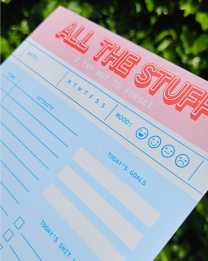 Funny and colorful A5 notepad with bold red and pink lettering, including to-do lists, goals, mood tracker and humorous sections like "Today’s Shit List" – designed by Dutch brand Studio Inktvis and printed in the Netherlands.