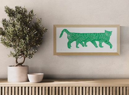 Horizontal risograph illustration of an unusually long green striped cat with a small pink detail, printed on white paper. Playful contemporary wall art for quirky interiors and cat lovers.