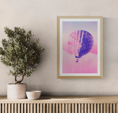 A3 risograph print of a pink and blue hot air balloon floating over dreamy clouds by PTRVRKD, hand-printed on 300 gsm Biotop paper.