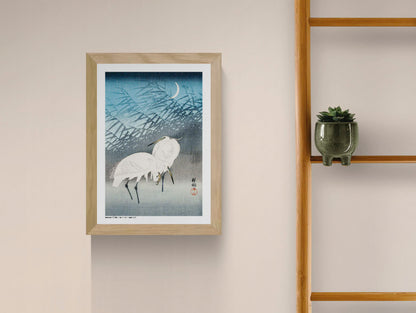 Two white egrets standing among layered reeds beneath a crescent moon, illustrated in a vintage Japanese woodblock style with blue and grey tones, vertical A4 digital print for calm wall decor.