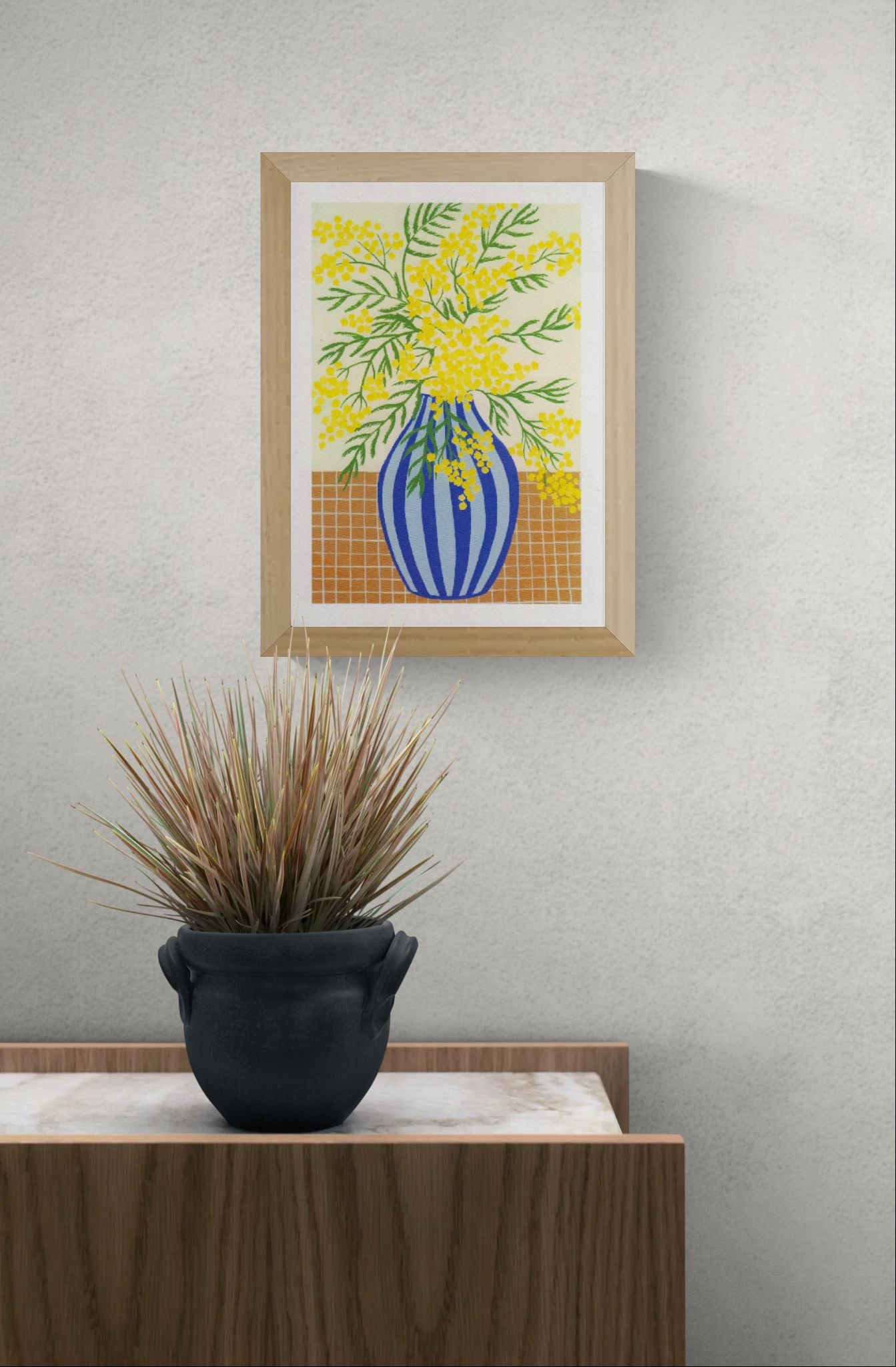 Botanical digital art print titled “Mimosa” by Belgian illustrator Leens, featuring vibrant yellow mimosa flowers in a blue striped vase on a tiled table, printed on textured fine art paper in A4 size.