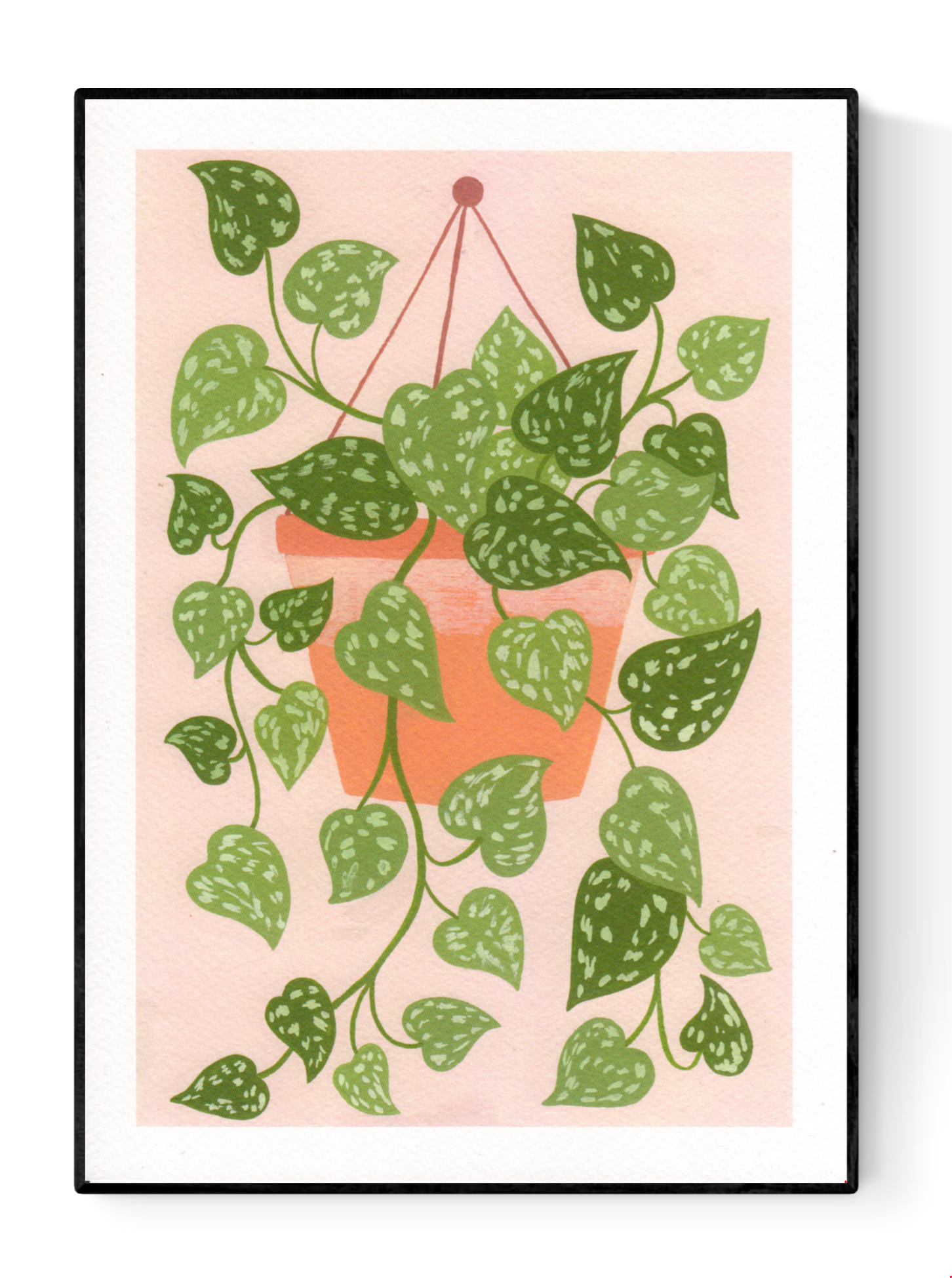 Digital art print titled “Scindapsus” by Belgian illustrator Leens, featuring a lush cascading houseplant with heart-shaped green leaves in a terracotta hanging pot, against a soft pink background. Printed on A4 fine art paper.
