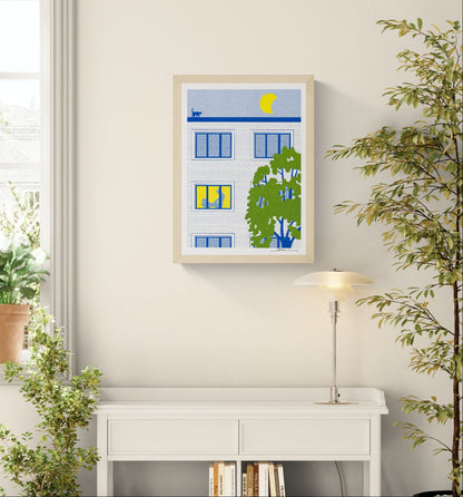 A3 risograph print of a modern apartment building at night with a bright yellow moon, rooftop cat, glowing window and playful silhouette scene, printed in bold blue, green and yellow tones. Contemporary humorous wall art for modern interiors.