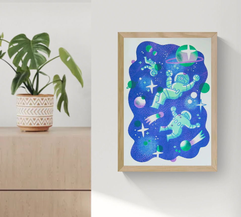 A3 limited edition risograph art print titled Space Quest by Belgian illustrator Auwnanas, featuring playful green astronauts floating in deep blue outer space with planets, stars, and graphic cosmic elements, contemporary wall art made in Belgium.