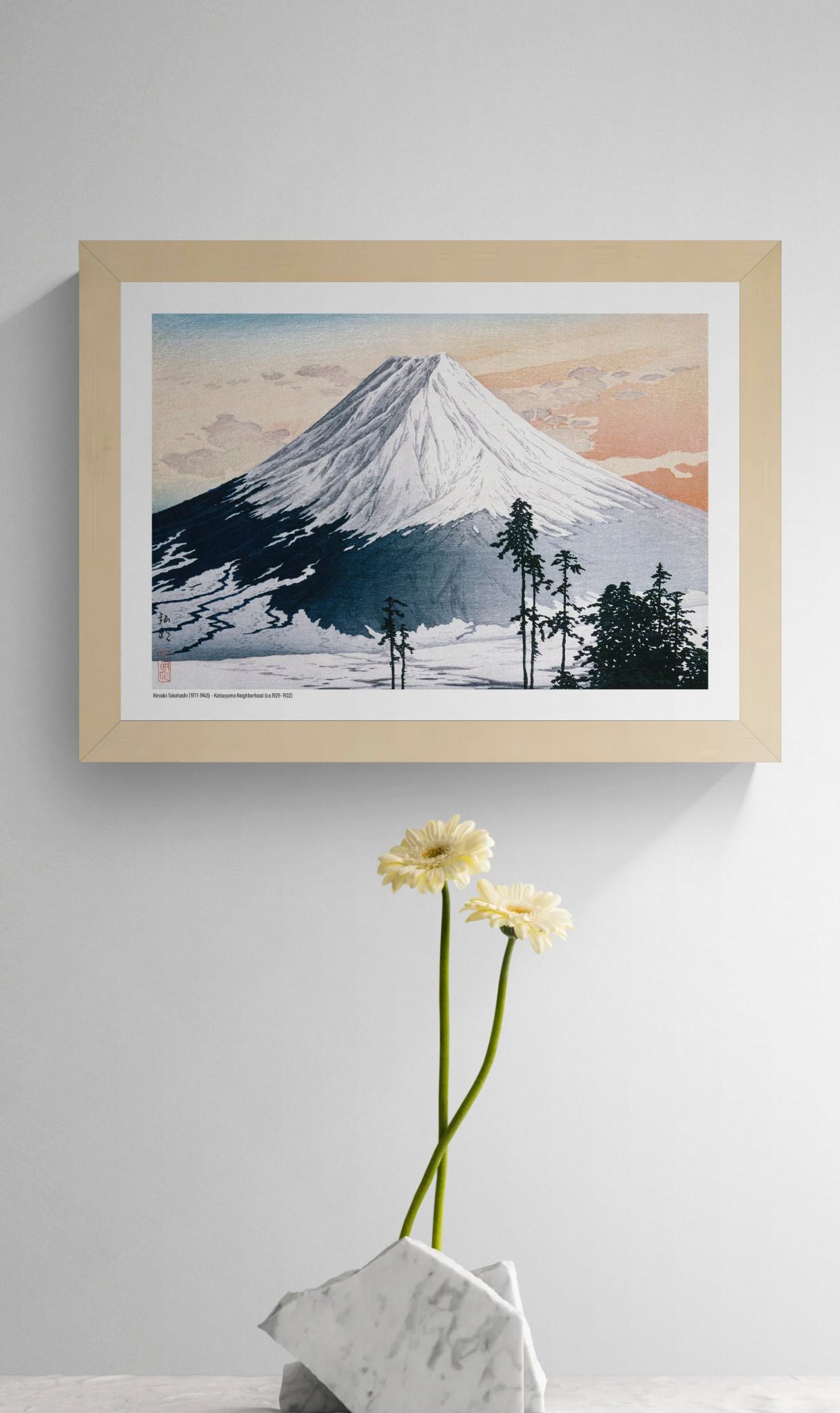 Landscape A4 art print of snow-covered Mount Fuji beneath a peach and blue sky, with dark pine trees in the foreground, based on a Japanese colour woodblock by Hiroaki Takahashi; horizontal wall art for calm interiors.