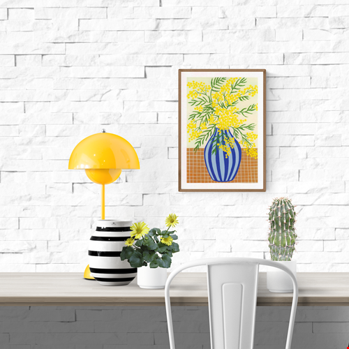 Botanical digital art print titled “Mimosa” by Belgian illustrator Leens, featuring vibrant yellow mimosa flowers in a blue striped vase on a tiled table, printed on textured fine art paper in A4 size.