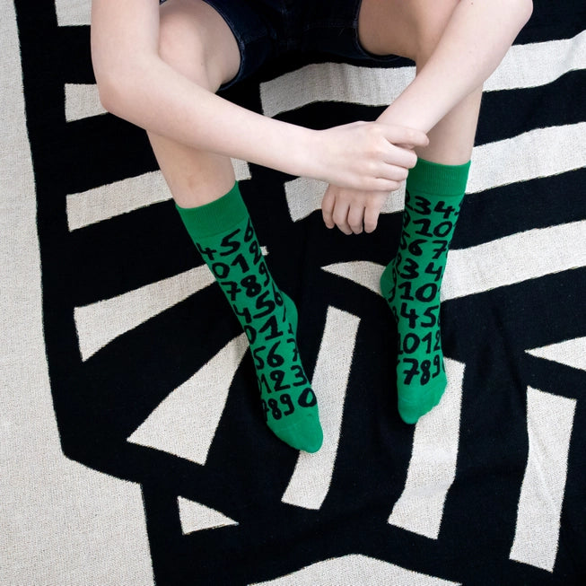 Green crew socks with playful black numbers by Sarah Corynen – unisex cotton blend, size 38-42, bold and quirky design for math fans and creative wardrobes.
