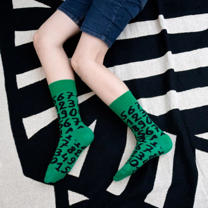 Green crew socks with playful black numbers by Sarah Corynen – unisex cotton blend, size 38-42, bold and quirky design for math fans and creative wardrobes.
