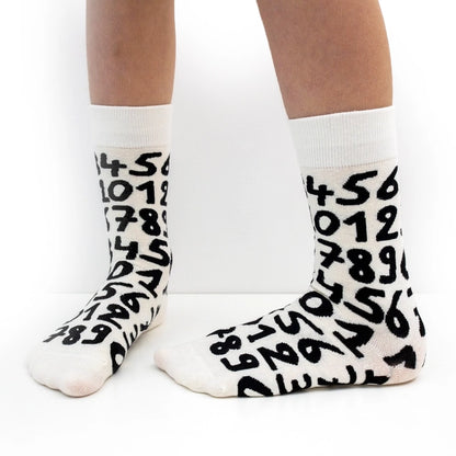 White crew socks with bold black numbers by Sarah Corynen – unisex cotton socks in size 38-42, playful illustrated design for math lovers and quirky everyday style.