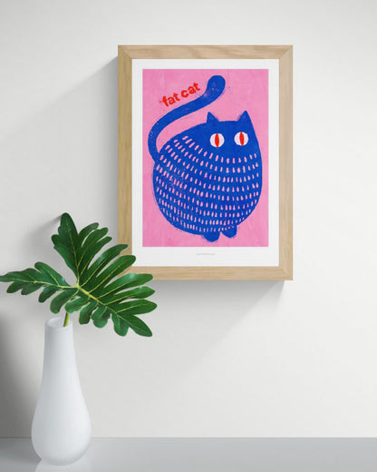 "Fat Cat" by Just Cool Design – playful and bold illustration of a chubby blue cat with red eyes on a vibrant pink background, featuring the text “fat cat”; a fun and colorful wall art print perfect for cat lovers and modern pop art enthusiasts, available at Galerie Frits