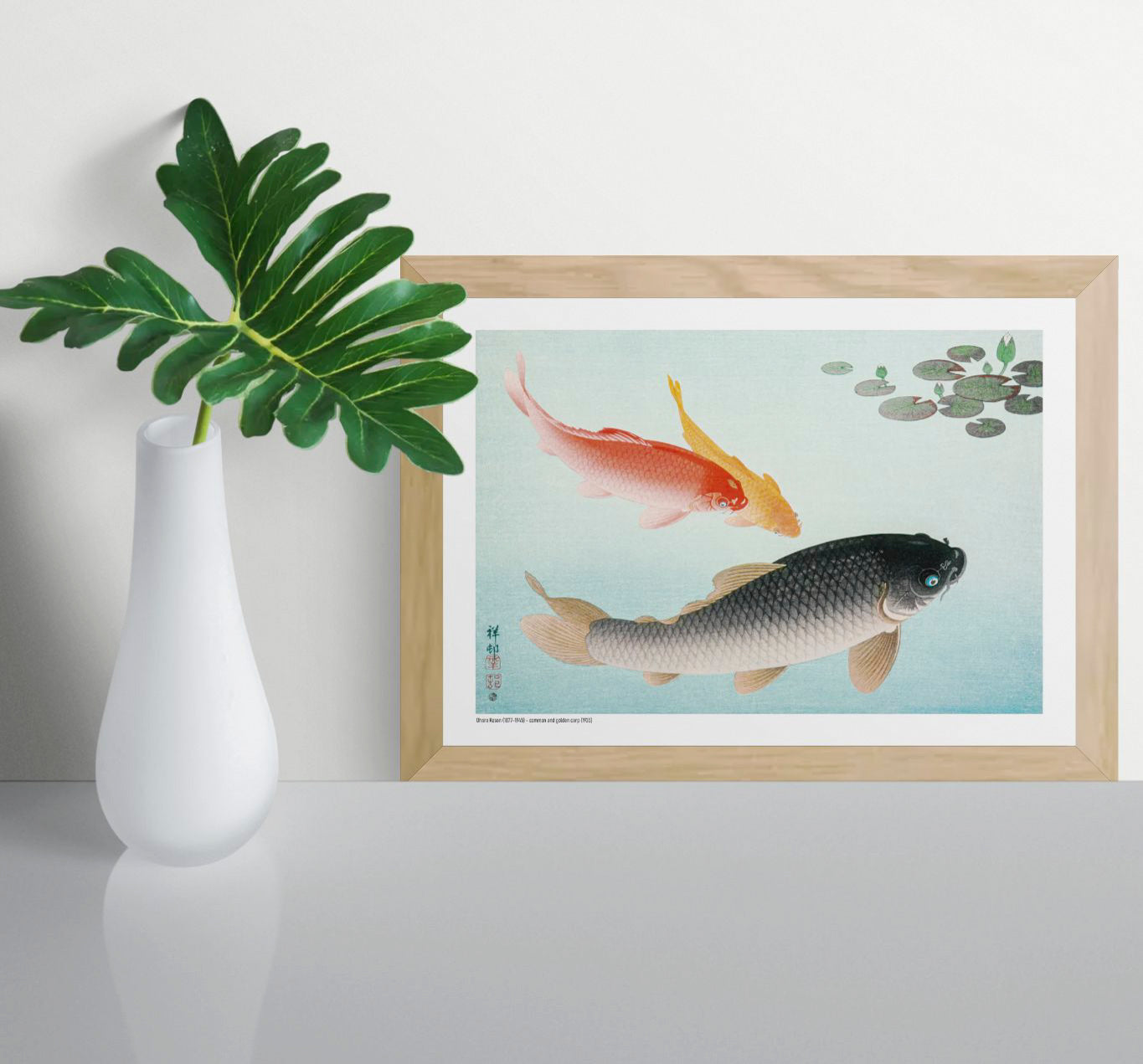 Horizontal Japanese art print by Ohara Koson showing red, golden and black carp swimming through pale blue water beneath dark green lily pads, ideal for calm living room or bedroom wall decor.