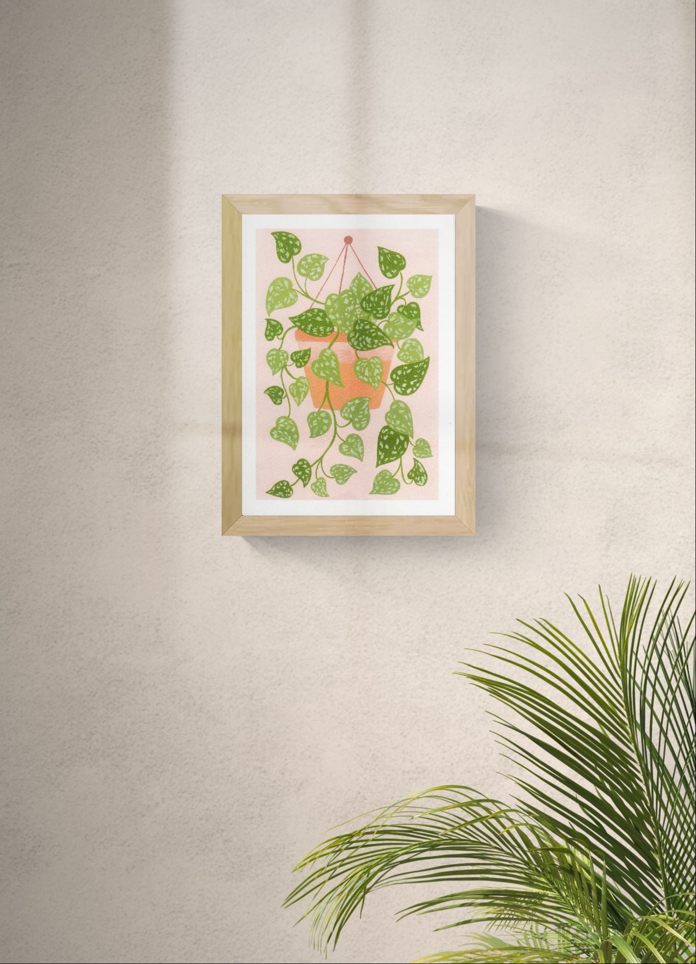 Scindapsus plant art print by Leens with cascading green leaves in a hanging terracotta pot on a blush pink background, modern botanical wall decor for cozy interiors.
