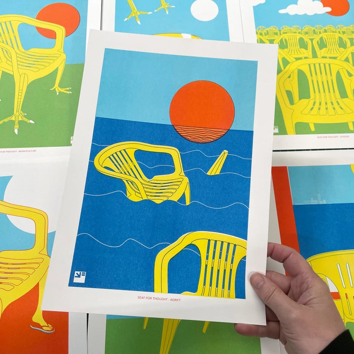 Bold graphic artwork by VrijFormaat depicting bright yellow plastic chairs adrift in deep blue ocean waves under a striking red sun. A minimalist, surreal scene evoking themes of climate change, nostalgia, and stillness—perfect for modern interiors and collectors of conceptual, thought-provoking art