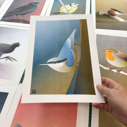 Illustration of a stylized nuthatch bird clinging to a tree in minimalist, soft blue and ochre tones – Nuthatch by VrijFormaat, A4 risograph art print made in the Netherlands.