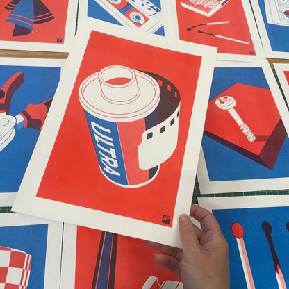 "Film Roll" by VrijFormaat – bold minimalist illustration of a retro 35mm film canister labeled “Ultra” in red, white, and blue, evoking vintage photography nostalgia and modern pop art aesthetics; a perfect gift for analog film lovers and creative wall decor, available at Galerie Frits