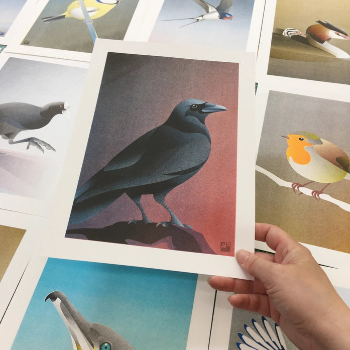 Atmospheric crow art print by Vrijformaat, featuring a sleek black crow against a moody gradient background of red and violet hues. A minimalist and elegant illustration perfect for modern interiors and bird lovers. Available at Galerie Frits