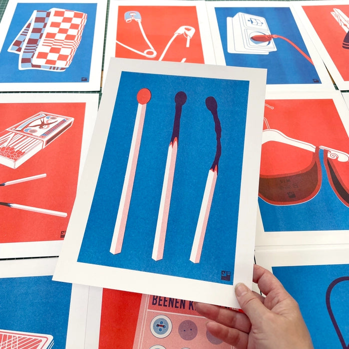 Minimalist risograph art print of three red and blue matchsticks in various stages of burning, designed by VrijFormaat on A4 Biotop paper.