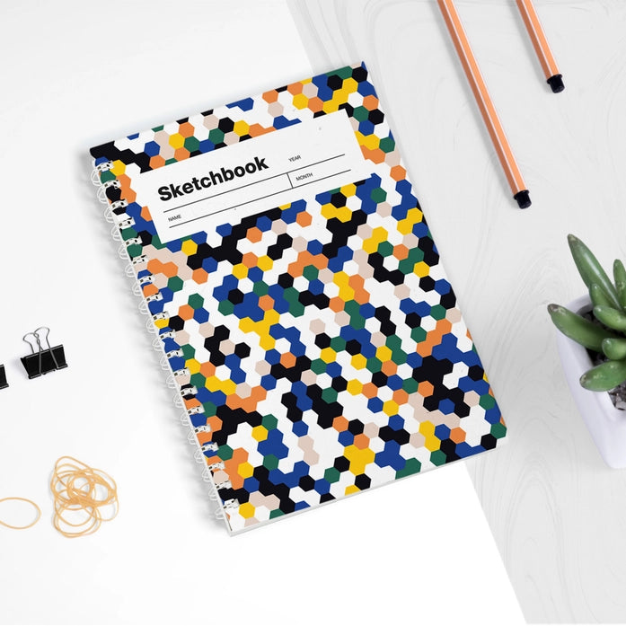Colorful mosaic A5 sketchbook by Weew Smart Design, featuring a vibrant hexagonal pattern cover and white spiral binding, with 100 blank pages on smooth 80gsm paper – perfect for daily sketching or creative