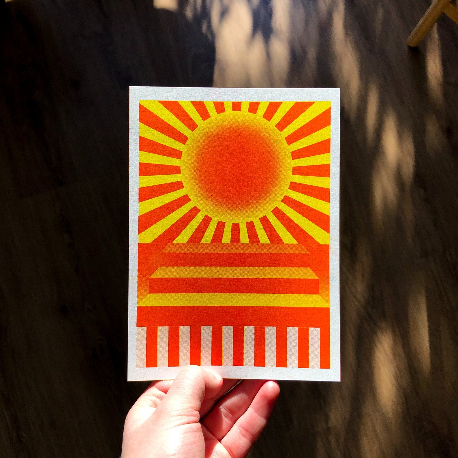 Yellow and red geometric risograph print by Dutch illustrator PTRVRKD – bold sunburst design with radiating rays, abstract stairs, and striped base, printed with eco-friendly soy inks on 250 gsm Biotop paper, handmade in the Netherlands – modern, colorful wall art full of energy.