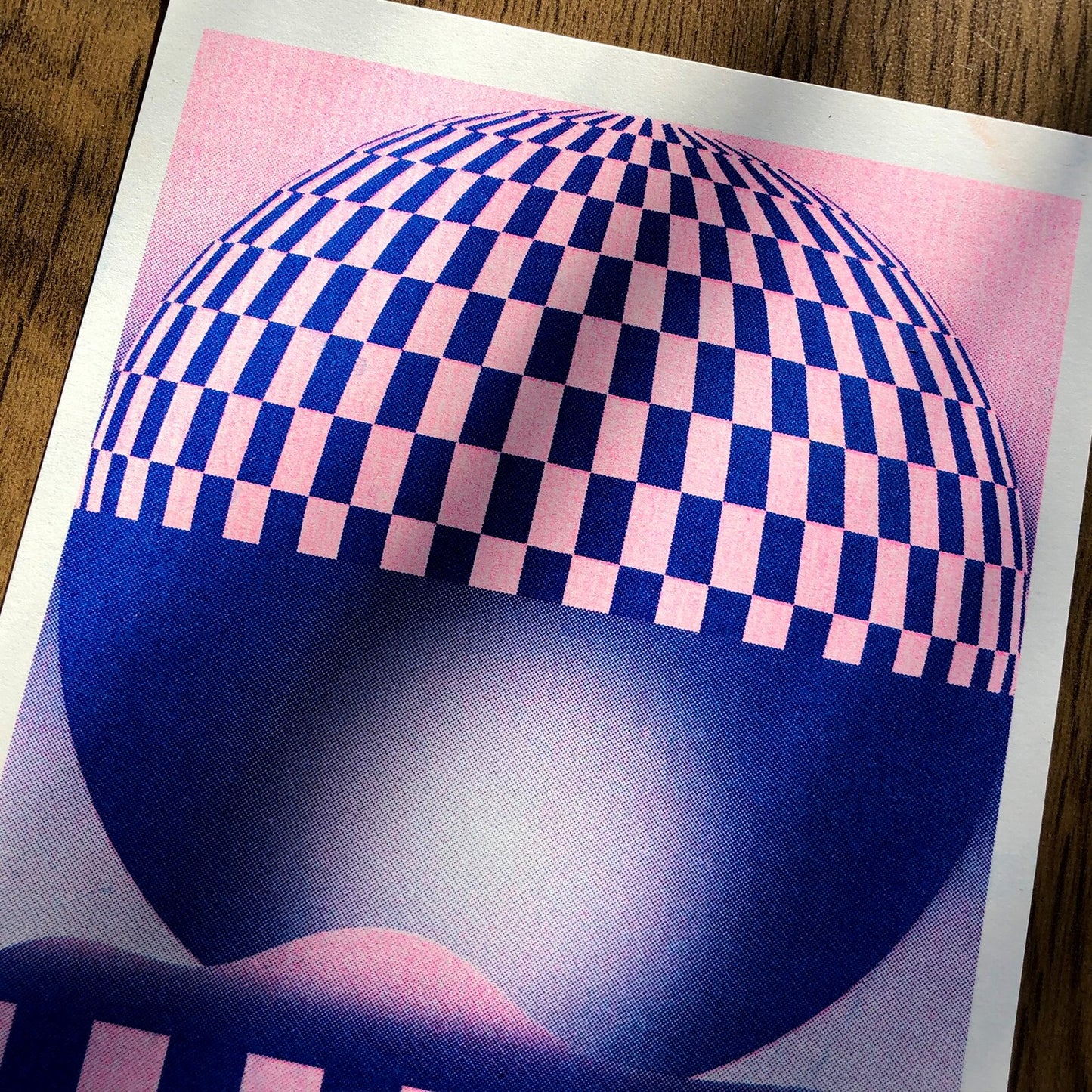 Pink and blue geometric risograph print by Dutch illustrator PTRVRKD – abstract optical landscape with checkerboard sphere, striped base, and dreamy gradient design, printed with eco-friendly soy inks on 250 gsm Biotop paper, handmade in the Netherlands – bold modern wall art for graphic design enthusiasts.