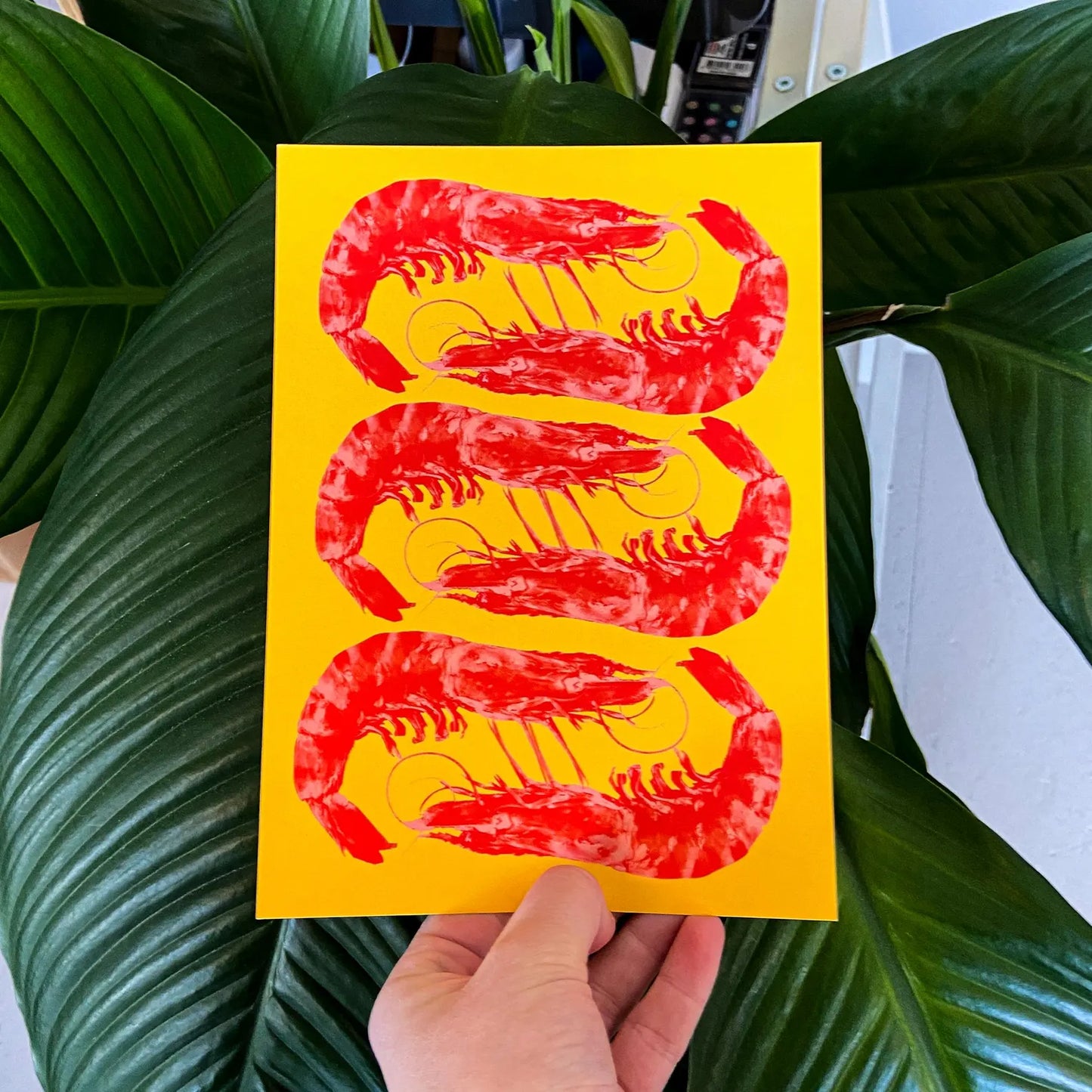 Bright yellow and red offset print of three shrimp by Dutch illustrator PTRVRKD – playful pop-art seafood design, bold color composition printed with eco-friendly soy inks on 250 gsm Biotop paper, handmade in the Netherlands – quirky small art print for modern kitchens or walls.