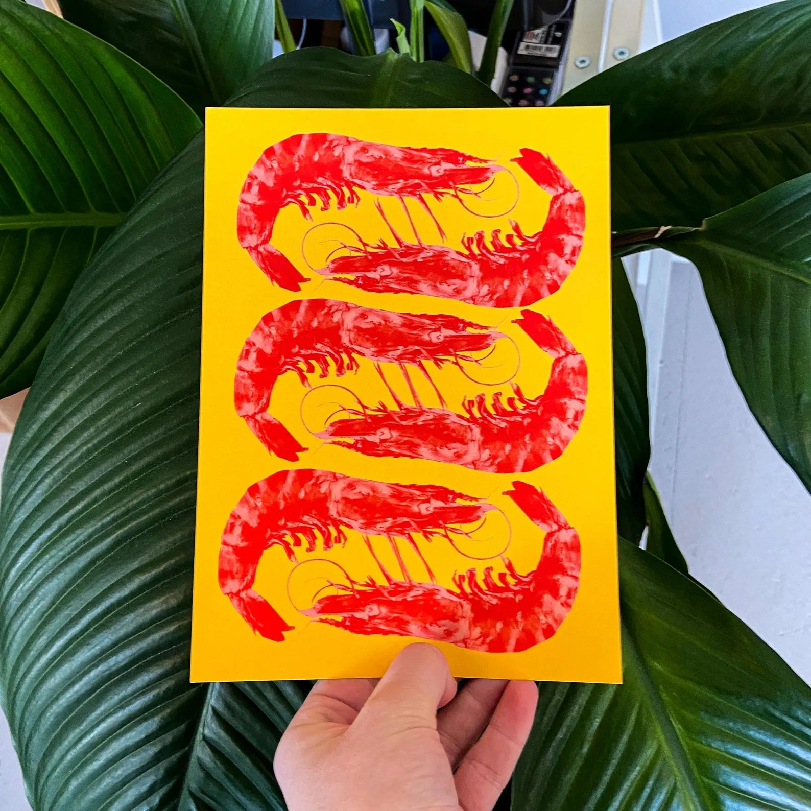 Bright yellow and red offset print of three shrimp by Dutch illustrator PTRVRKD – playful pop-art seafood design, bold color composition printed with eco-friendly soy inks on 250 gsm Biotop paper, handmade in the Netherlands – quirky small art print for modern kitchens or walls.