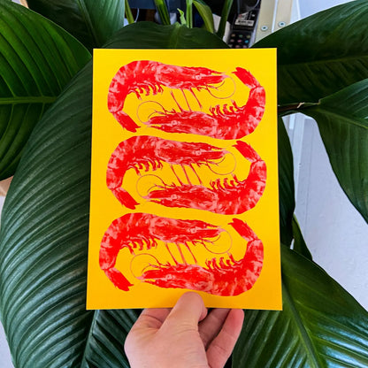 Bright yellow and red offset print of three shrimp by Dutch illustrator PTRVRKD – playful pop-art seafood design, bold color composition printed with eco-friendly soy inks on 250 gsm Biotop paper, handmade in the Netherlands – quirky small art print for modern kitchens or walls.