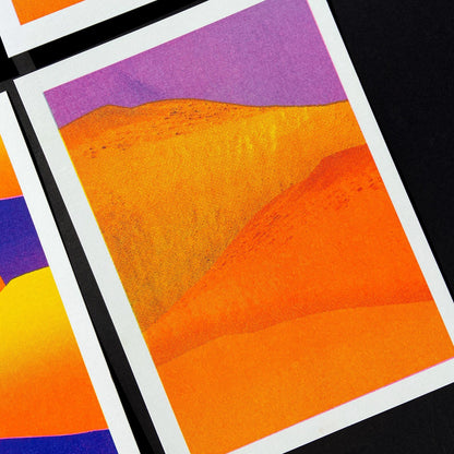 Vibrant yellow and orange sand dunes with bold purple sky, minimalist 13x18 cm risograph landscape print by PTRVRKD, handmade in the Netherlands.