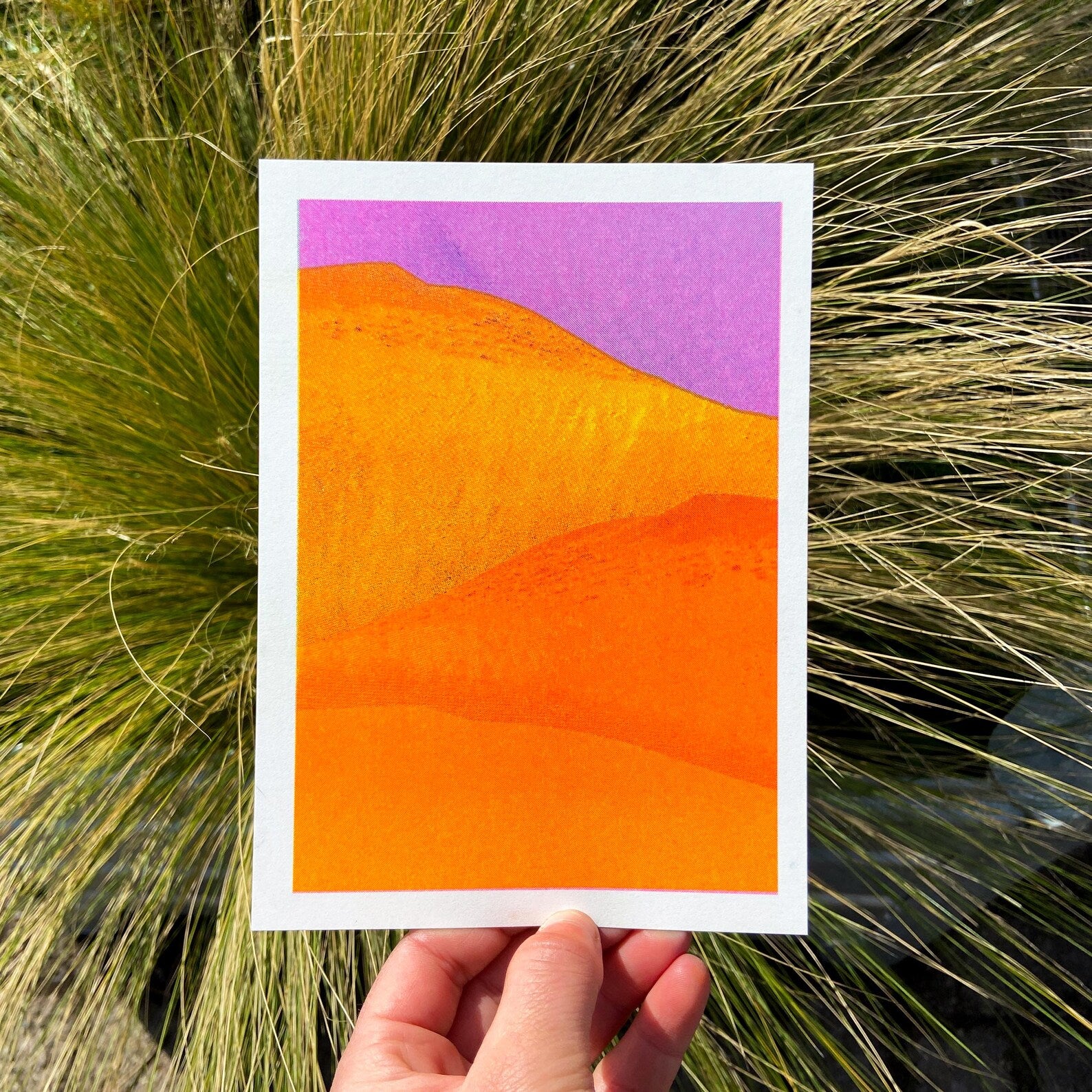 Vibrant yellow and orange sand dunes with bold purple sky, minimalist 13x18 cm risograph landscape print by PTRVRKD, handmade in the Netherlands.