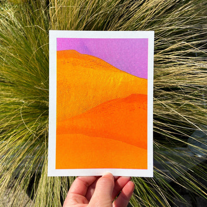 Vibrant yellow and orange sand dunes with bold purple sky, minimalist 13x18 cm risograph landscape print by PTRVRKD, handmade in the Netherlands.