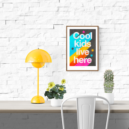 Giclée art print by Just Cool Design with the phrase "Cool kids live here" in bold white letters over a bright rainbow background with stars, ideal for colorful children's rooms or playful modern decor.