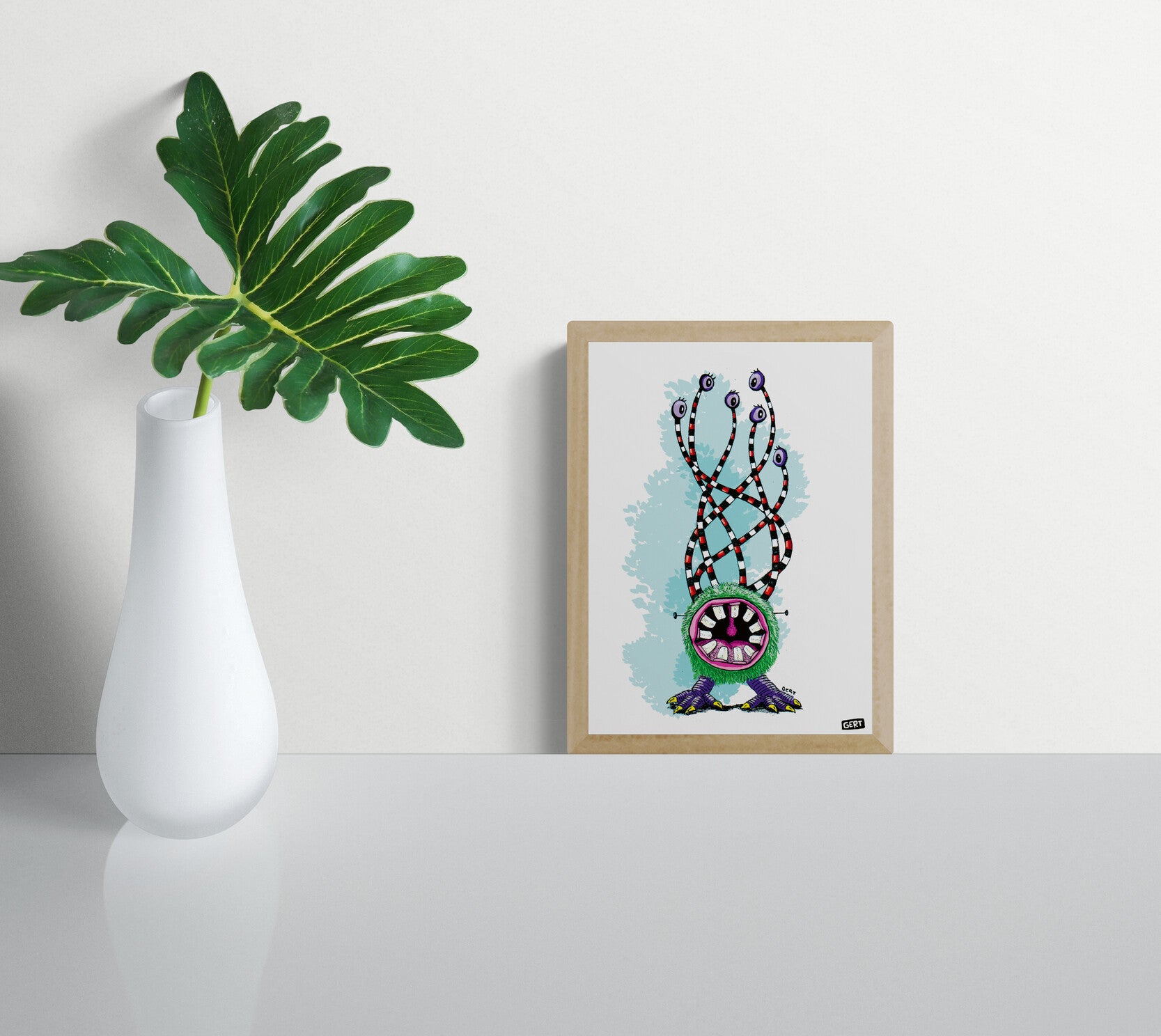 Monster 2 by Gert Paenen, colorful monster art print featuring a furry green creature with a large mouth, striped eyestalks, multiple purple eyes, and playful fantasy character design on a light blue background, contemporary Belgian illustration wall art.
