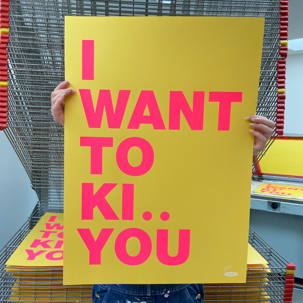 Large handmade screenprint with bold pink and yellow text reading "I want to ki.. you" — playful, humorous poster by Dutch studio Gumbootz, ideal for modern interiors and statement walls.